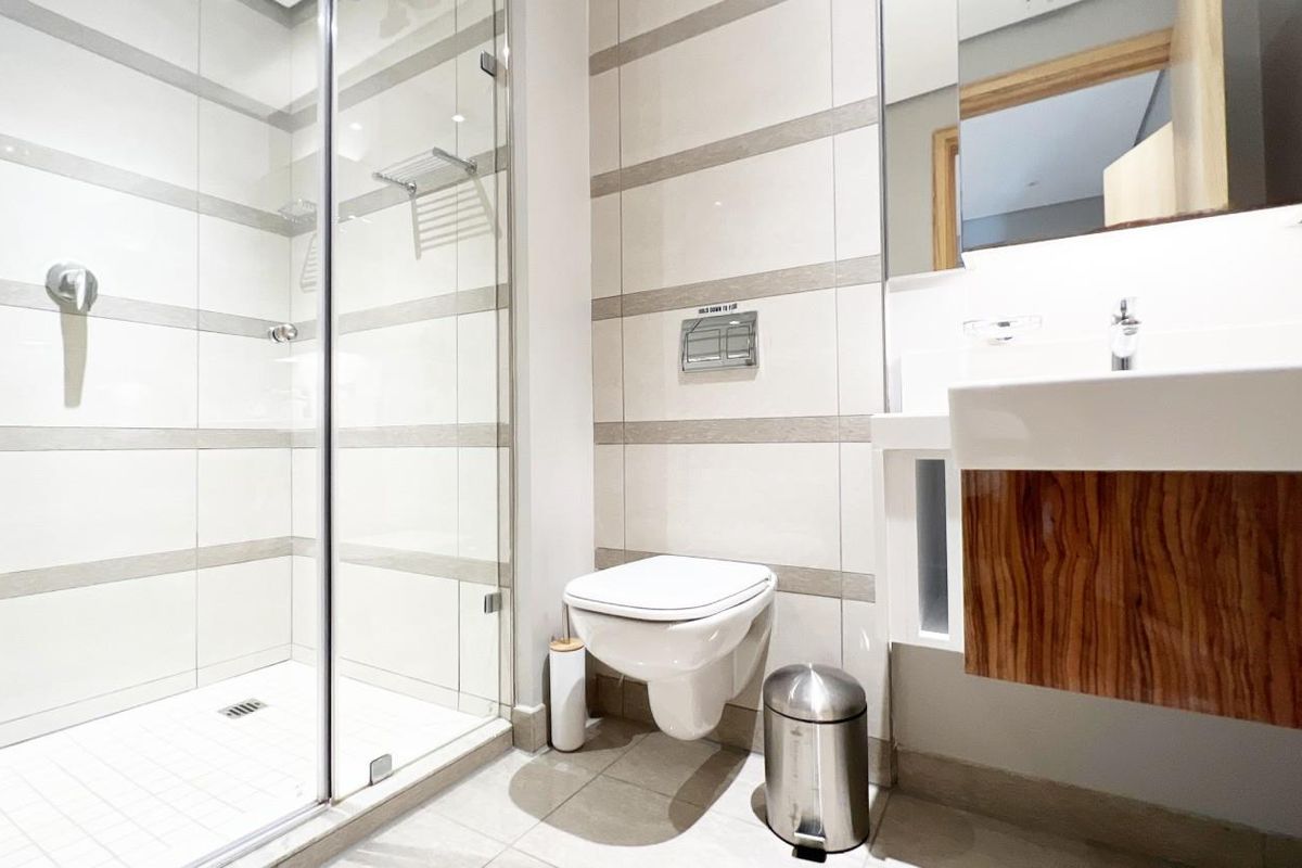 Modern bathroom featuring a glass-enclosed walk-in shower, wall-mounted toilet, and a contemporary vanity with integrated basin.