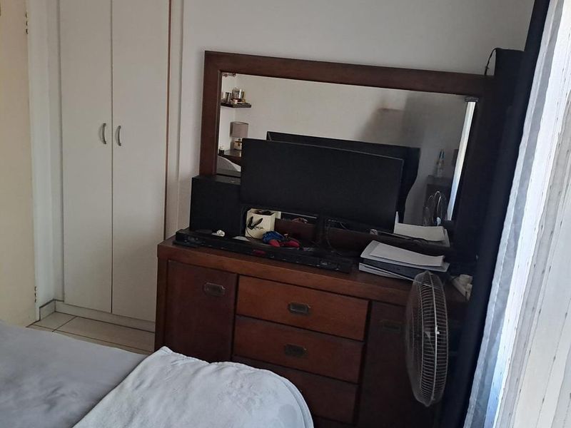 A bedroom featuring a built-in wardrobe and tiled flooring, providing functional storage space within the apartment.