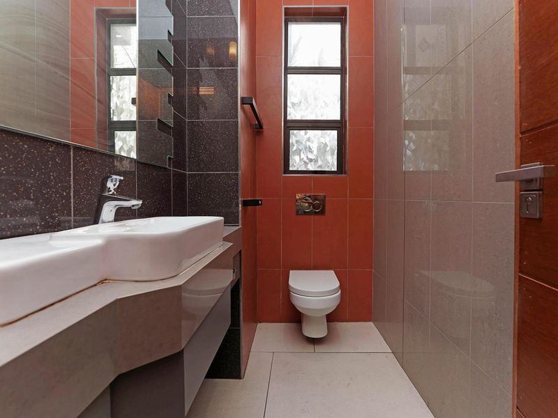 Modern bathroom featuring a wall-mounted toilet with concealed cistern, vanity basin with mixer tap, and contemporary tiled finishes.
