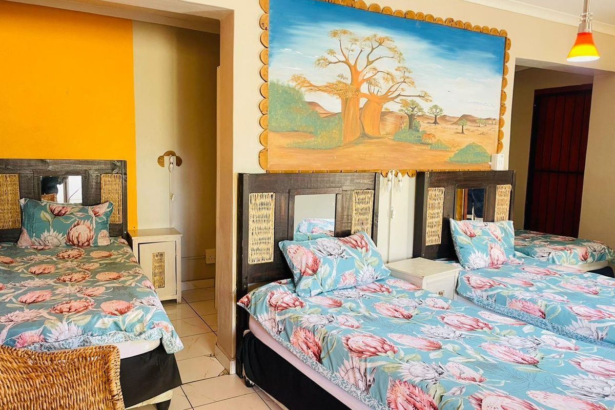 A bedroom featuring tiled flooring, cove cornicing, and a pendant light fixture, currently configured with multiple beds.