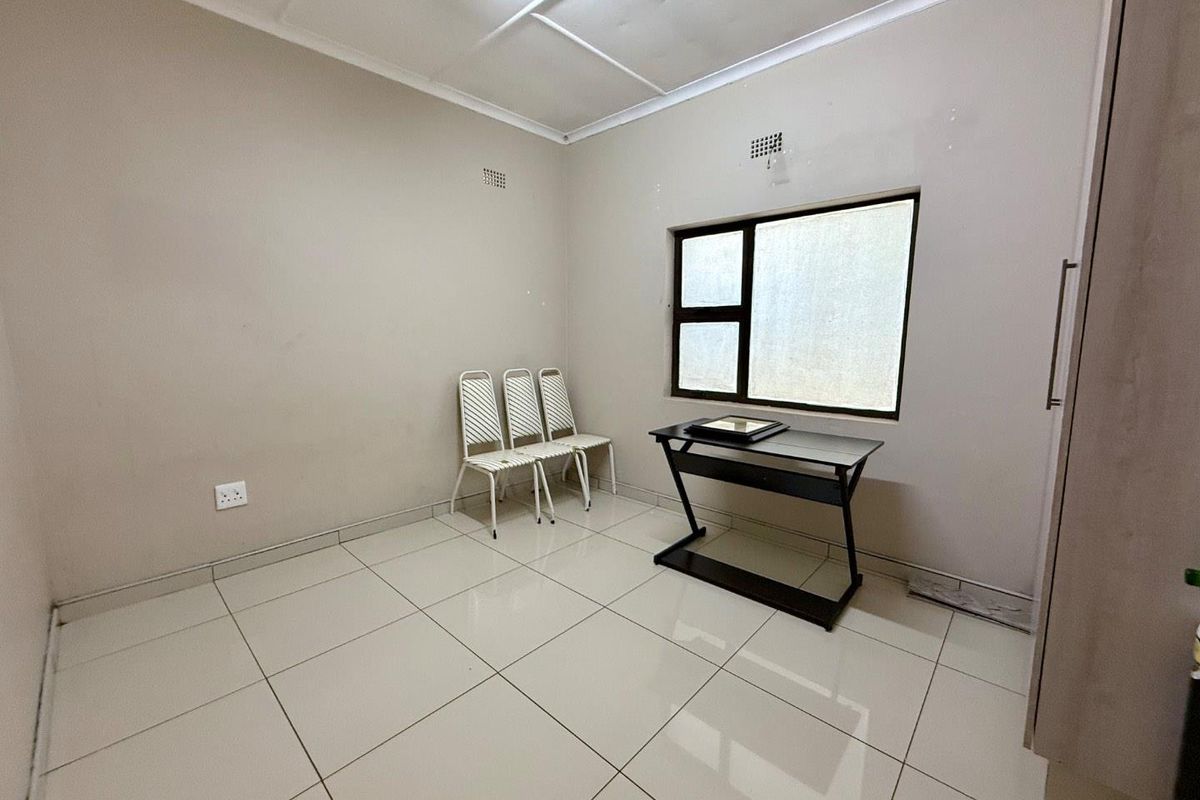 A simple bedroom featuring tiled flooring, a window with privacy film, and neutral wall finishes.