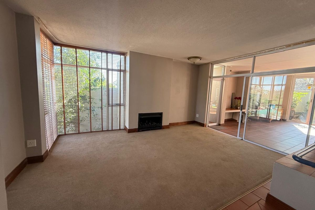 Spacious living room featuring a built-in fireplace, large windows, and sliding glass doors leading to an adjacent patio area.