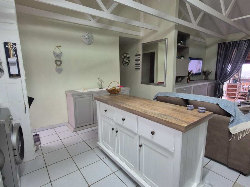 Open-plan living area featuring exposed roof trusses, tiled flooring, and a central kitchen island, creating a functional and connected living space.