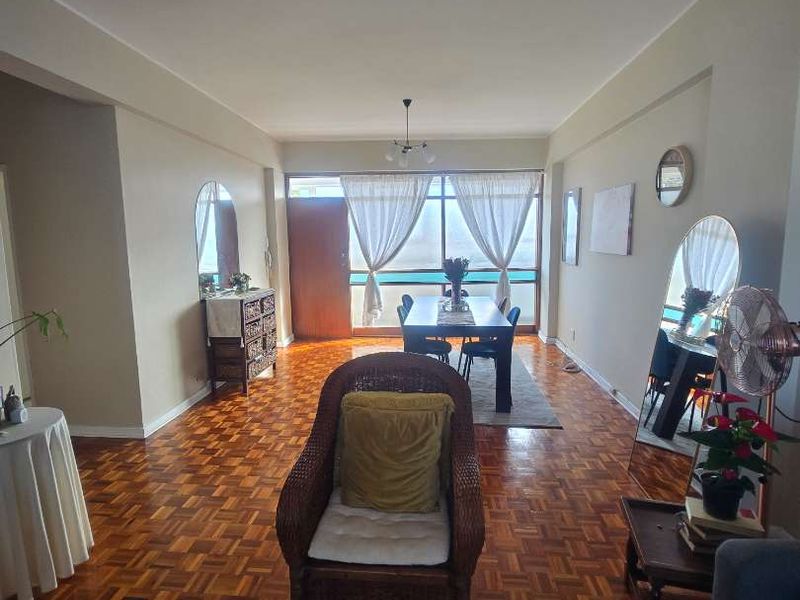 Spacious open-plan living and dining area featuring classic parquet flooring and large sliding glass doors that provide natural light.