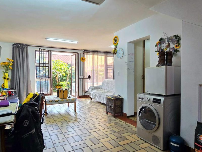 Open-plan living area featuring tiled flooring and direct access to the garden through a security-fitted sliding door.