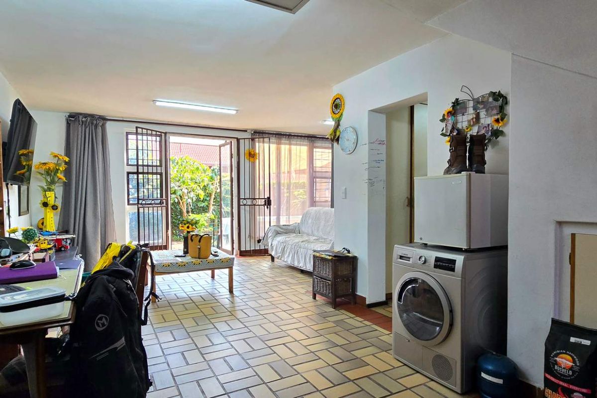 Open-plan living area featuring tiled flooring and direct access to the garden through a security-fitted sliding door.
