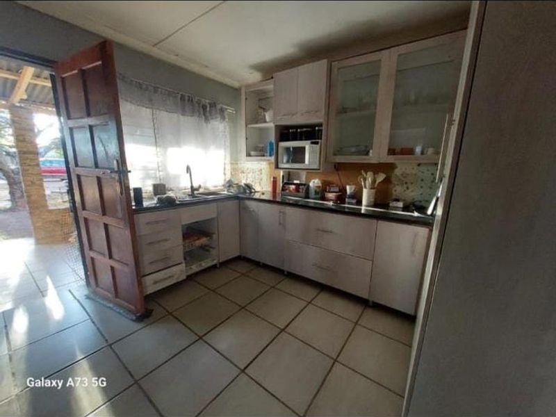 A functional kitchen featuring built-in cabinetry, laminate countertops, and tiled flooring, with direct access to an outdoor patio area.