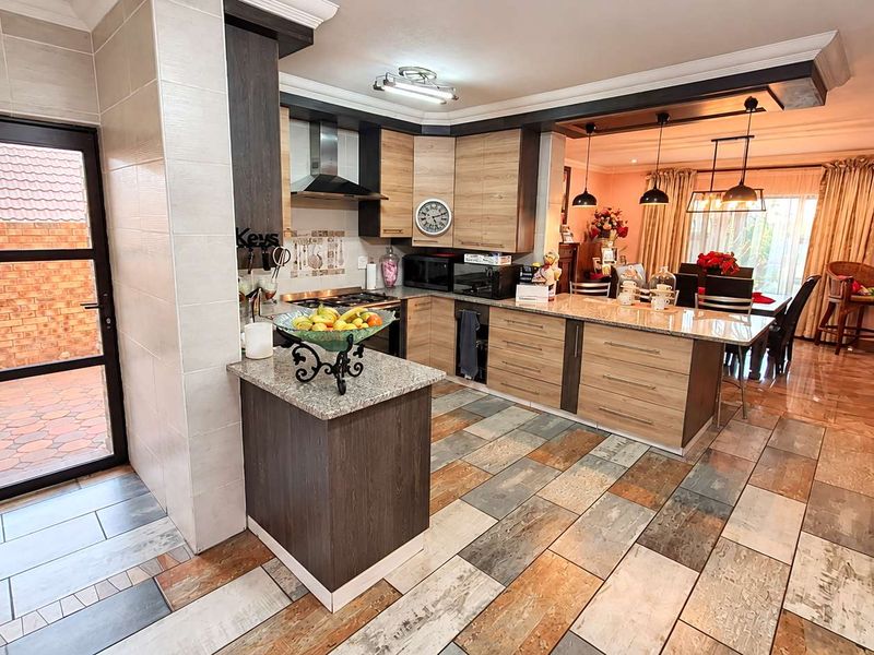 Spacious open-plan kitchen and dining area featuring modern cabinetry, granite countertops, and stylish tiled flooring with integrated lighting fixtures.