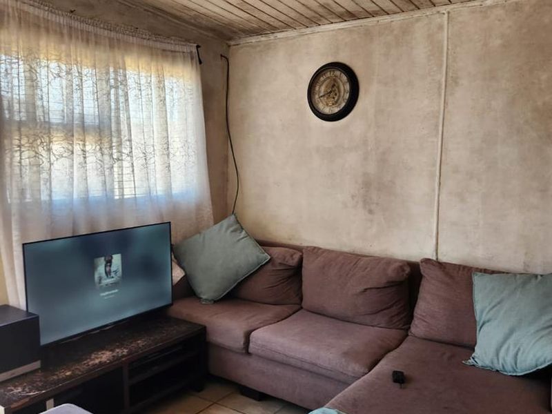 A living room featuring tiled flooring and a timber panelled ceiling, currently requiring cosmetic updates to the wall and ceiling finishes.