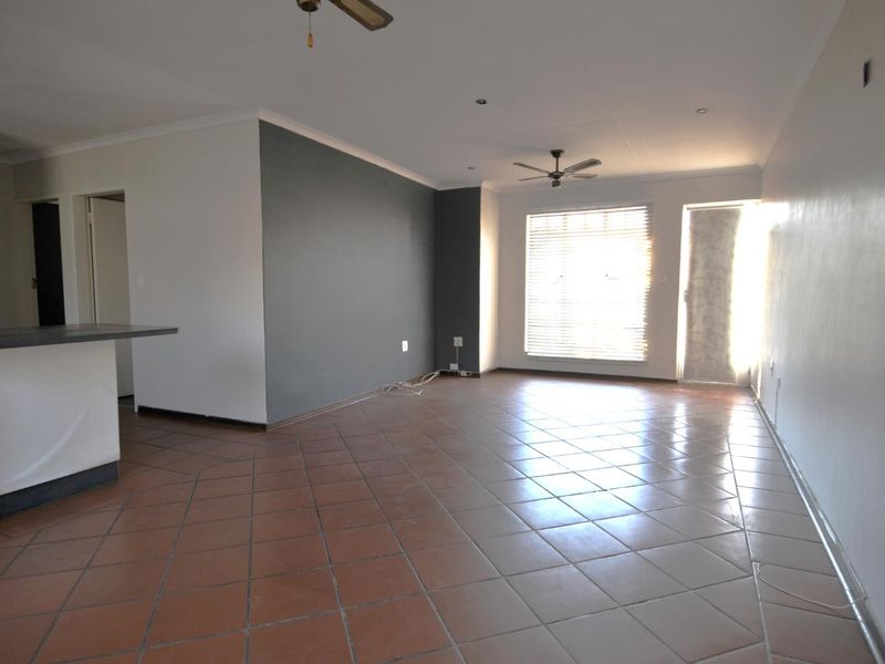 Spacious open-plan living area featuring tiled flooring, ceiling fans, and a breakfast bar, offering a versatile layout for dining and relaxation.