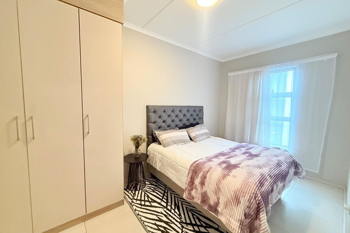 A well-lit bedroom featuring built-in cabinetry, tiled flooring, and a window with curtain tracks.