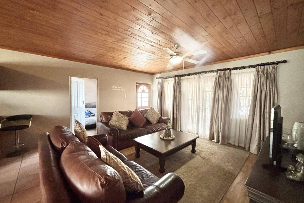 A comfortable living room featuring a warm timber plank ceiling, ceiling fan, and sliding glass doors that provide natural light and access to the outdoors.