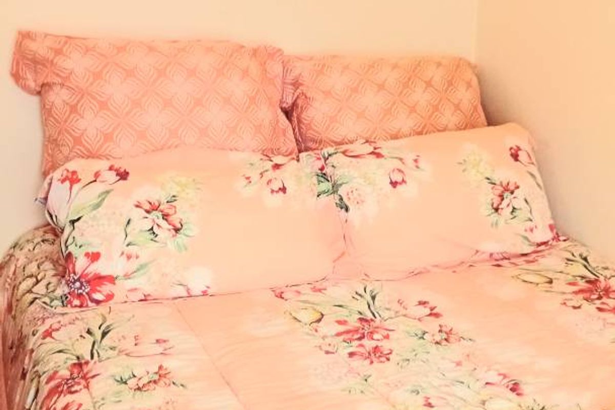 A bedroom interior featuring a bed with floral bedding and a wall-mounted picture.