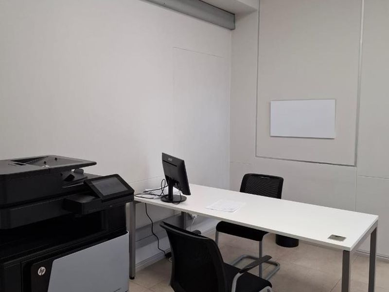 A functional office space featuring tiled flooring, recessed lighting, and a wall-mounted split-system air conditioner.