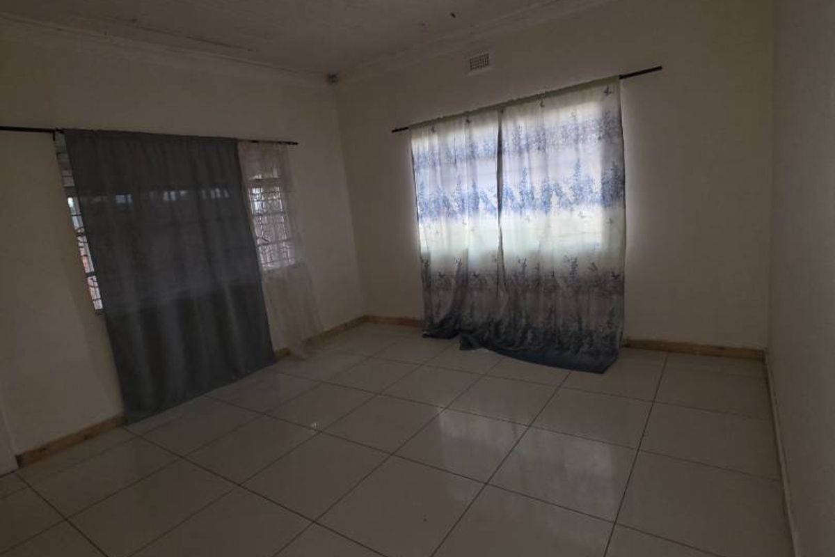 An empty living room featuring tiled flooring and a timber plank ceiling, offering a blank canvas for renovation and interior design.