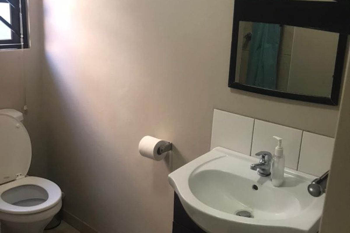 A functional bathroom featuring a vanity cabinet with a basin, a toilet, and a wall-mounted mirror.