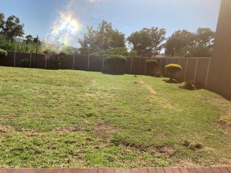 A spacious private garden area featuring a lawn and enclosed by a precast concrete boundary wall.