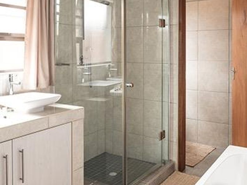 A well-maintained bathroom featuring a glass-enclosed shower, tiled flooring, and a modern vanity with a countertop basin.