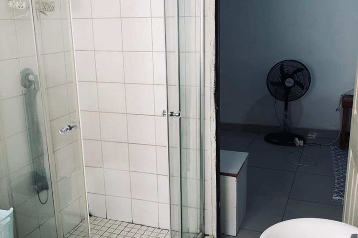 A functional bathroom featuring a glass-enclosed shower with tiled walls and a pedestal basin, providing a clean and practical layout.