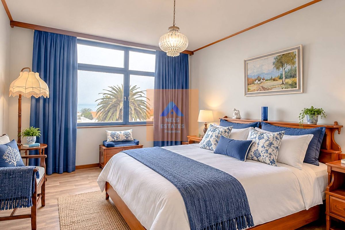 A well-maintained bedroom featuring large windows with natural light, laminate flooring, and classic timber trim details.