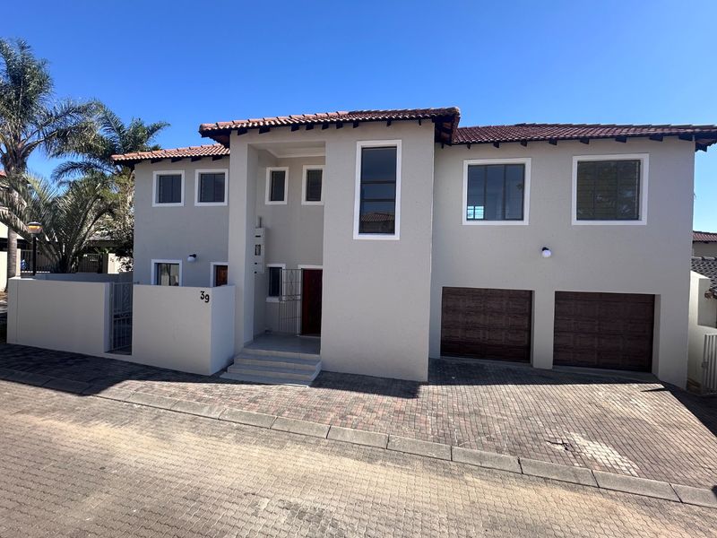 A modern double-story residential property featuring a paved driveway, double garage, and secure boundary wall with a clean, well-maintained facade.
