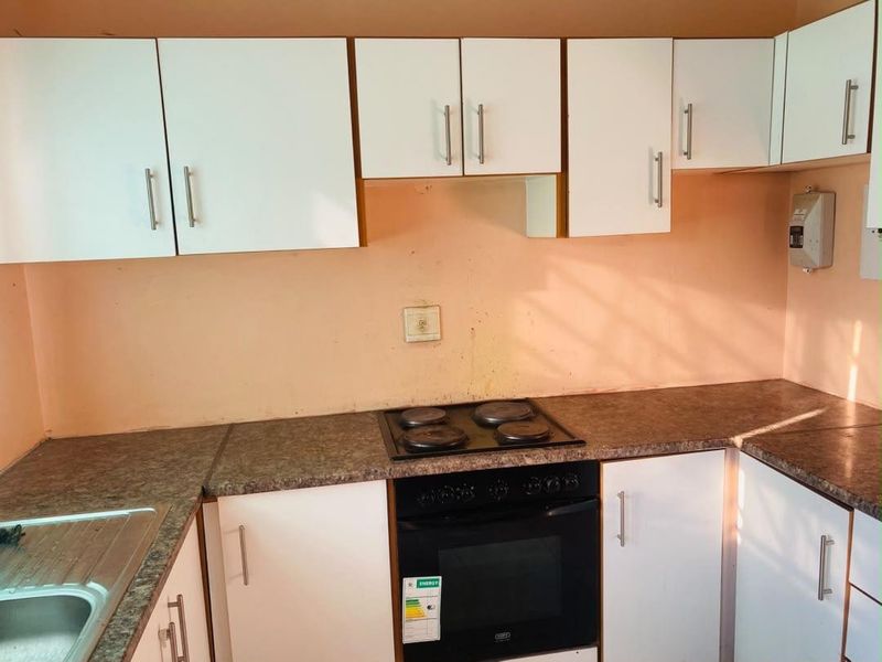 A functional kitchen featuring white cabinetry, laminate countertops, and a built-in electric oven and hob, ready for cosmetic updates.