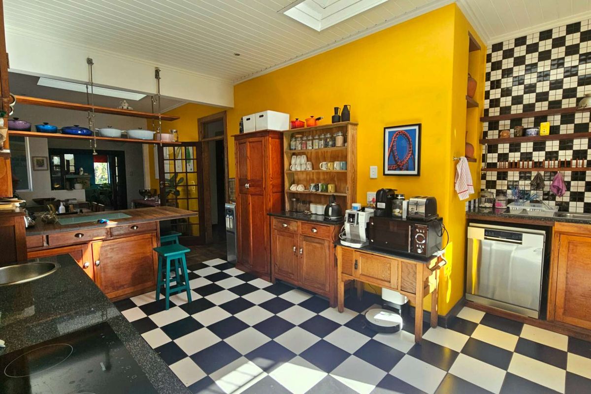 A characterful kitchen featuring wooden cabinetry, granite countertops, a checkerboard tiled floor, and a skylight, offering a unique and warm aesthetic.