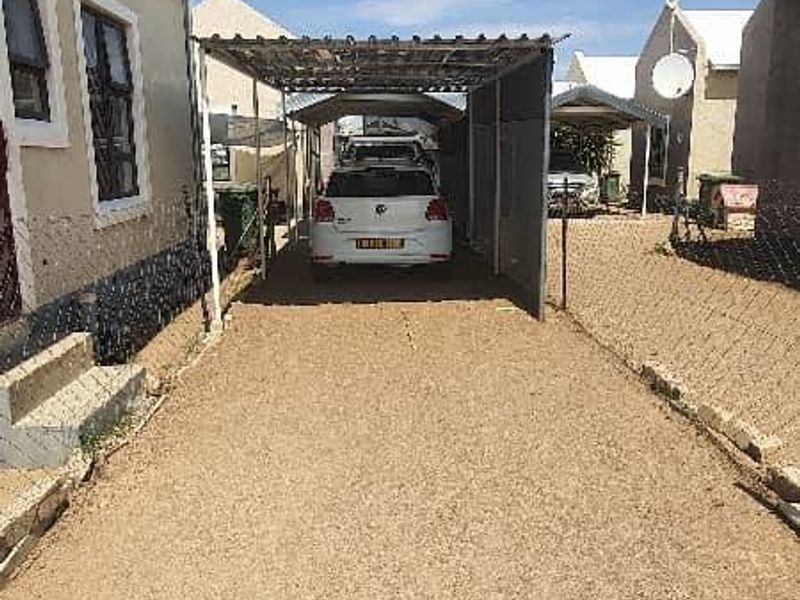 Exterior view of the property featuring a gravel driveway and a covered carport structure.