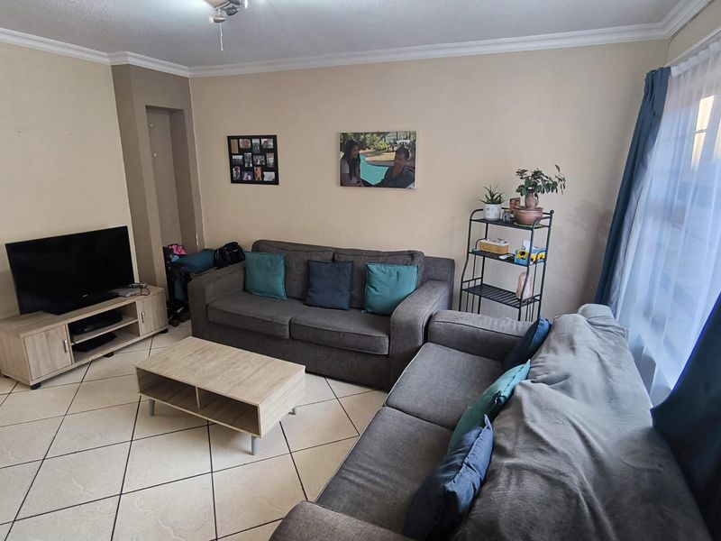 A comfortable living room featuring tiled flooring, cove cornicing, and a built-in wall niche, providing a functional and well-lit space for relaxation.