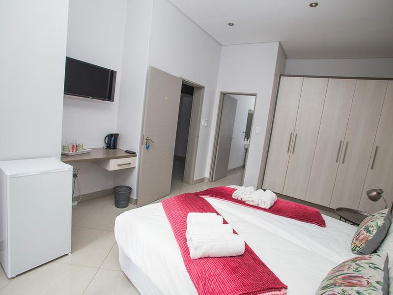 A well-maintained bedroom featuring neutral tiled flooring, built-in wardrobes, and a functional built-in desk area with recessed lighting.
