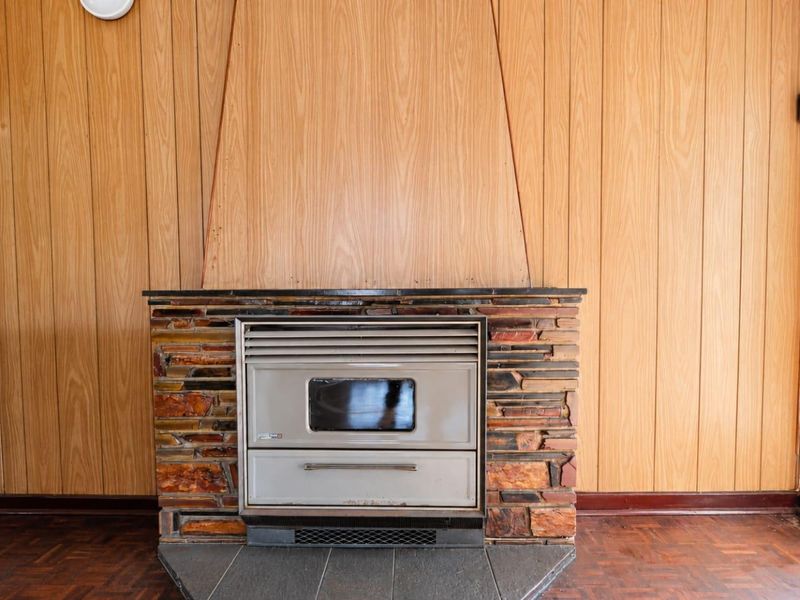 Living room featuring a built-in fireplace with a stone surround, wood paneling walls, and parquet flooring.