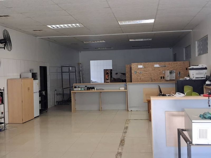 Open-plan office space featuring tiled flooring, a suspended ceiling with recessed lighting, and a built-in service counter area.