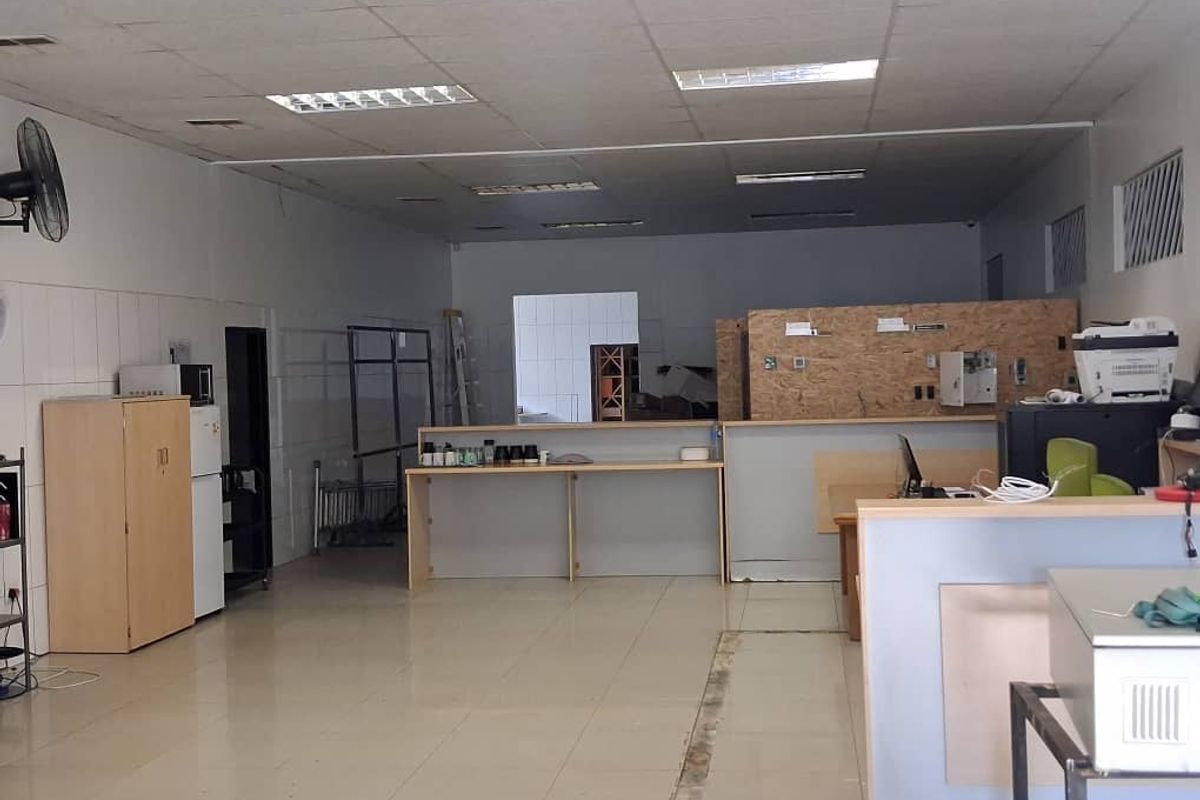 Open-plan office space featuring tiled flooring, a suspended ceiling with recessed lighting, and a built-in service counter area.