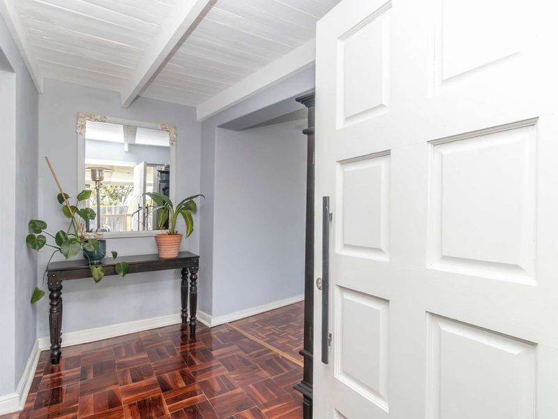 Welcoming entrance hall featuring classic parquet flooring and a white panelled front door with exposed beam ceiling details.