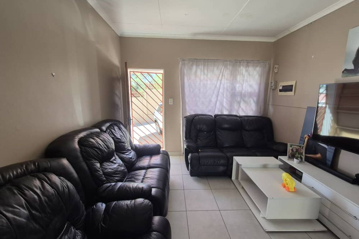 A living room featuring tiled flooring, a security gate at the entrance, and a wall-mounted electrical distribution board.
