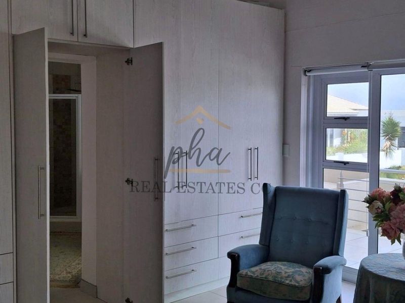 A well-maintained bedroom featuring extensive built-in cabinetry, neutral finishes, and direct access to an outdoor balcony through large sliding glass doors.