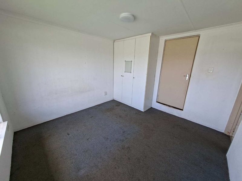 An empty bedroom featuring built-in wardrobe storage, carpet flooring, and neutral wall finishes, ready for a refresh.