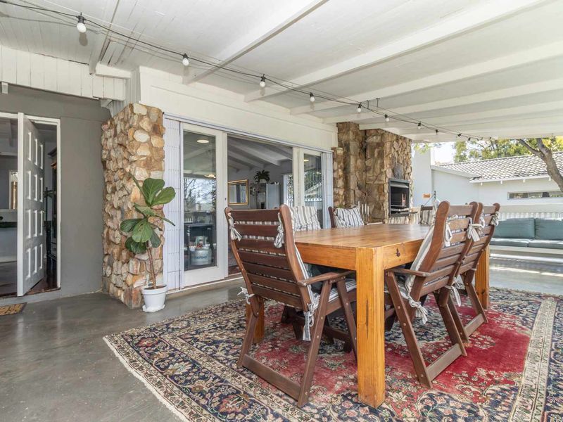 Covered outdoor patio featuring stone-clad pillars, a built-in fireplace, and exposed beam ceilings, providing a seamless transition to the interior living space.