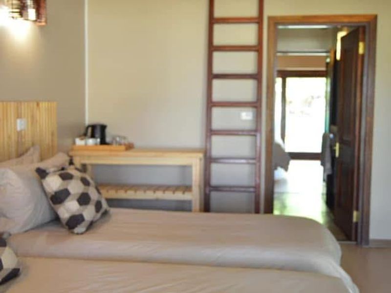 A bedroom featuring a high vaulted thatched ceiling with exposed timber rafters and a mezzanine loft area accessible via a wooden ladder.