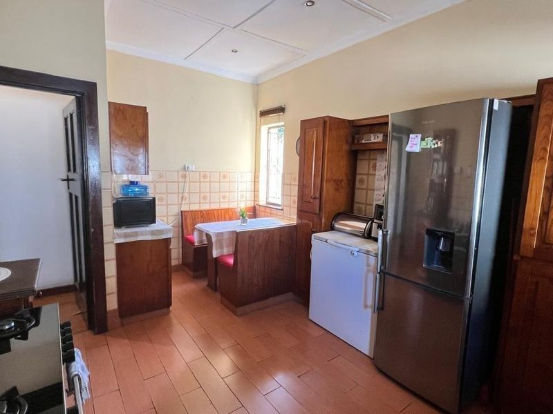 A functional kitchen featuring wooden cabinetry, a built-in breakfast nook, and terracotta flooring, offering a traditional layout with potential for modern updates.