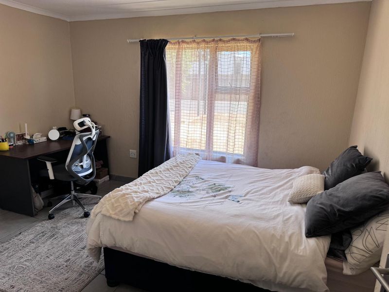 A functional bedroom featuring tiled flooring and a window with a curtain rod, providing a neutral space ready for personalization.