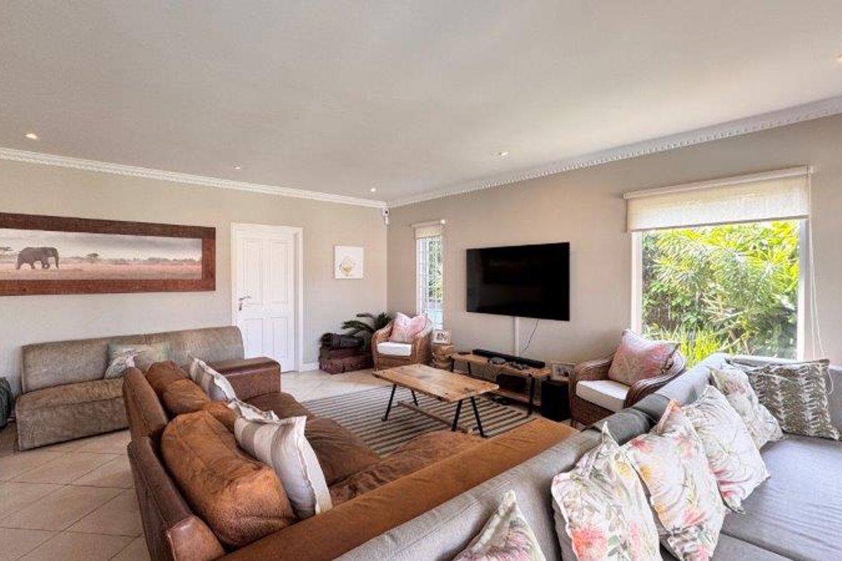 Spacious living room featuring tiled flooring, recessed downlighting, crown molding, and large windows with roller blinds, creating a bright and comfortable atmosphere.