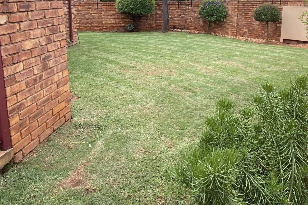 A private rear garden featuring a built-in brick braai area, established lawn, and perimeter brick walling.