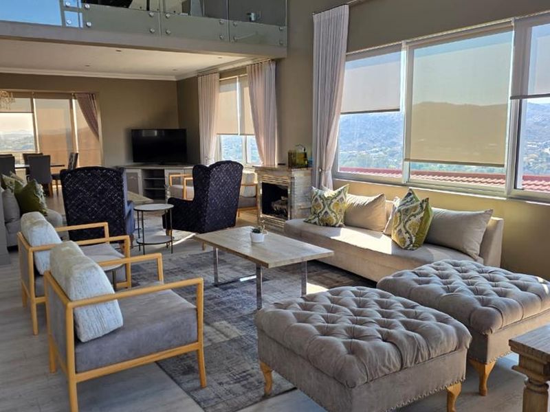 Spacious open-plan living area featuring a mezzanine level with glass balustrade, a cozy fireplace, and large windows offering expansive views.