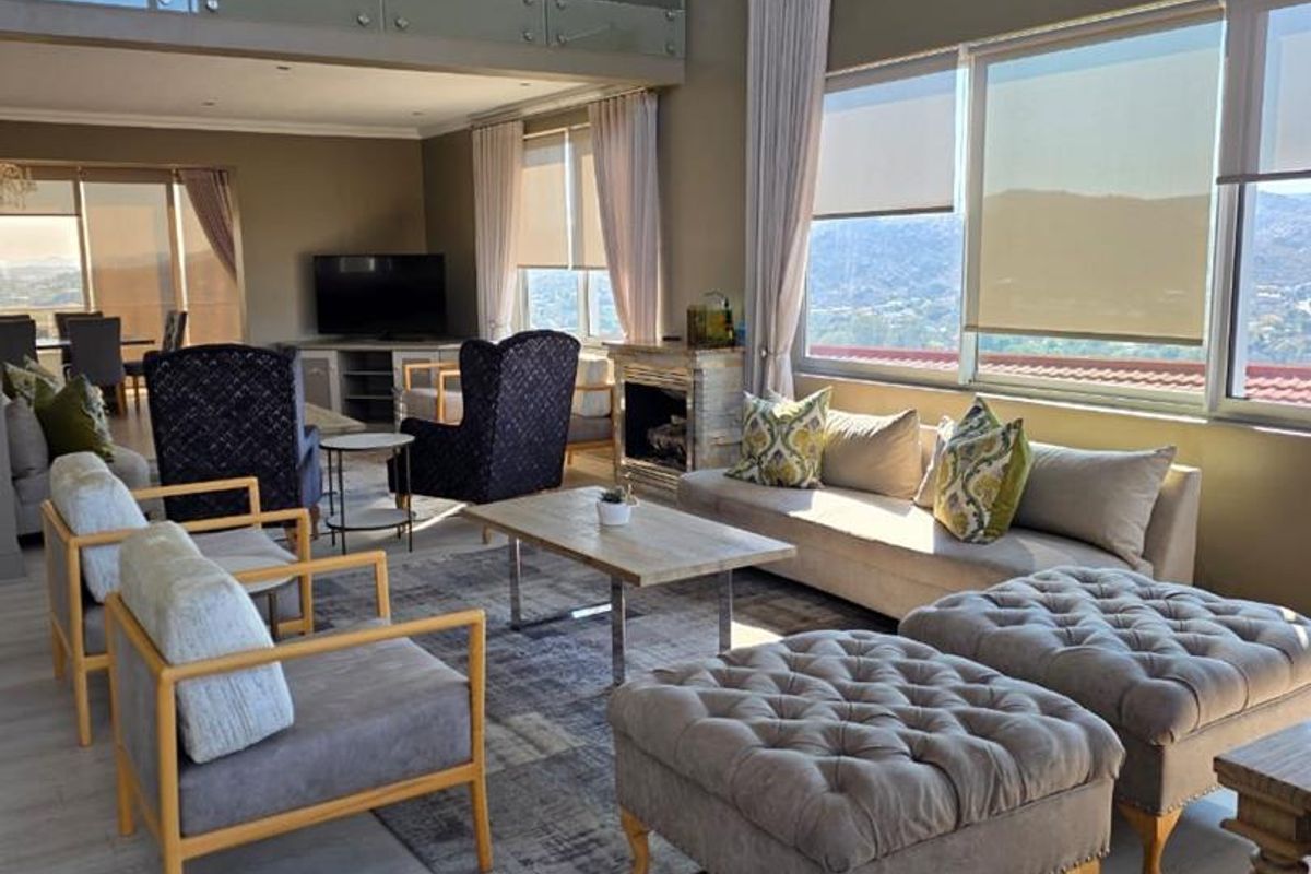 Spacious open-plan living area featuring a mezzanine level with glass balustrade, a cozy fireplace, and large windows offering expansive views.