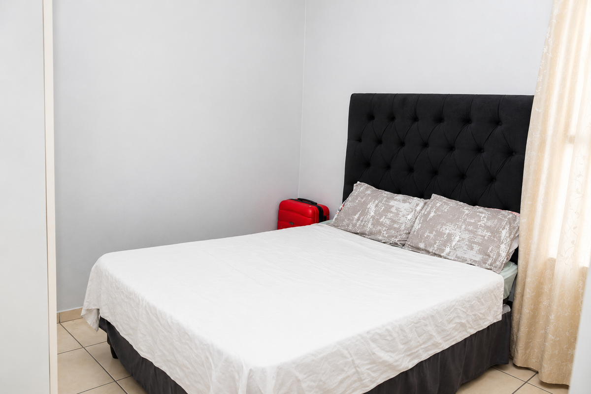 A bedroom featuring tiled flooring and neutral wall finishes, providing a simple and functional sleeping space.