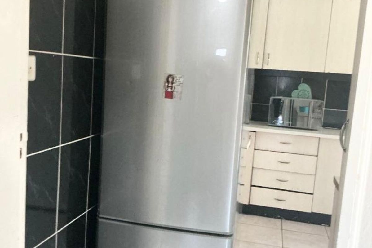 A functional kitchen area featuring built-in cabinetry, tiled splashbacks, and tiled flooring, viewed from an adjacent space.