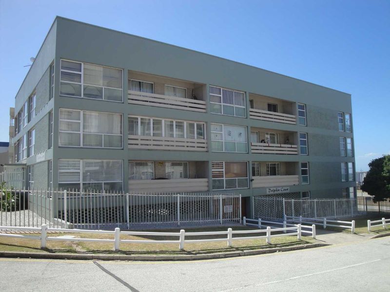 Exterior view of Dolphin Court apartment building featuring multi-level balconies, large windows, and secure perimeter fencing.