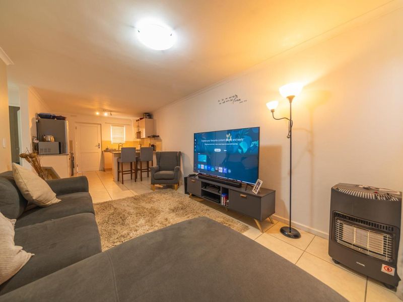 Open-plan living area featuring tiled flooring and a functional kitchen with a breakfast counter, creating a cohesive and practical living space.