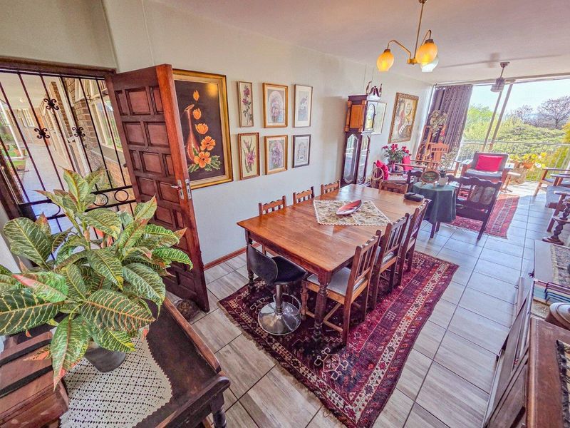 Open plan living and dining area featuring tiled flooring, a security gate at the entrance, and access to an outdoor balcony space.